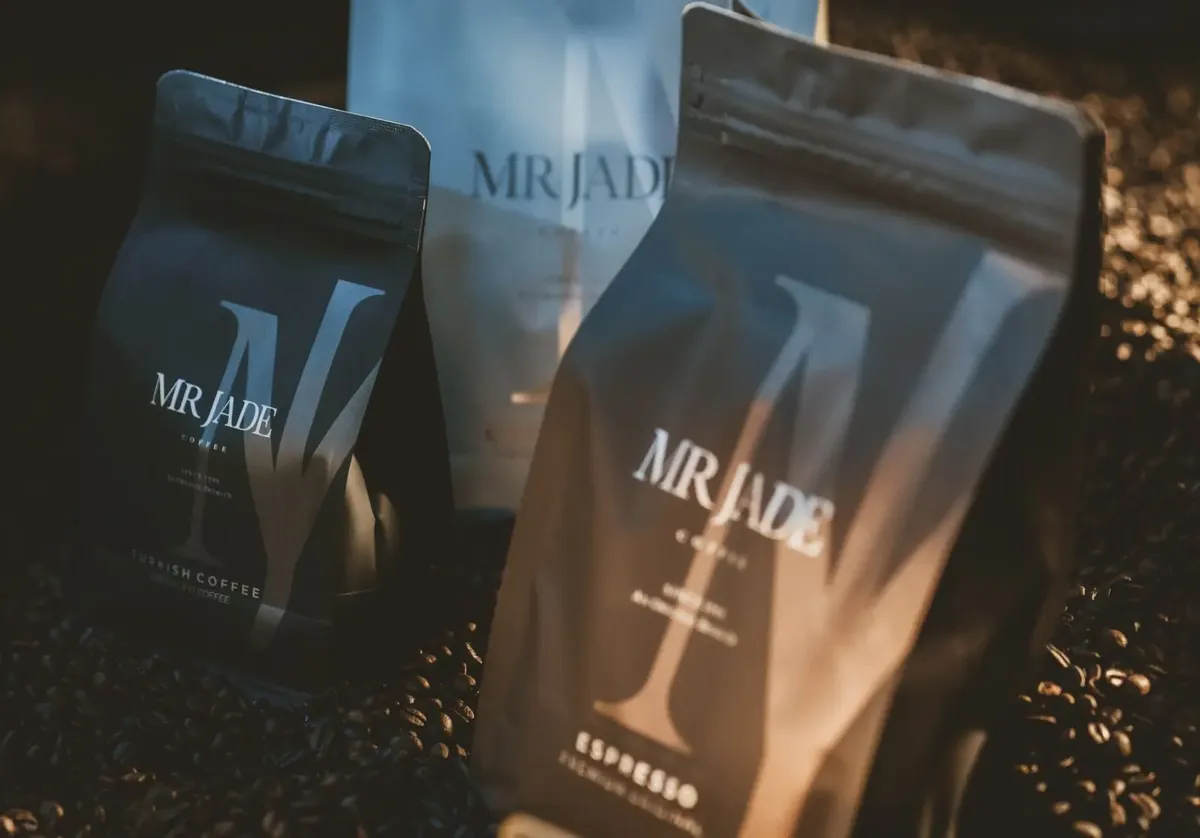 MR JADE Turkish Coffee and Espresso bags resting on roasted coffee beans