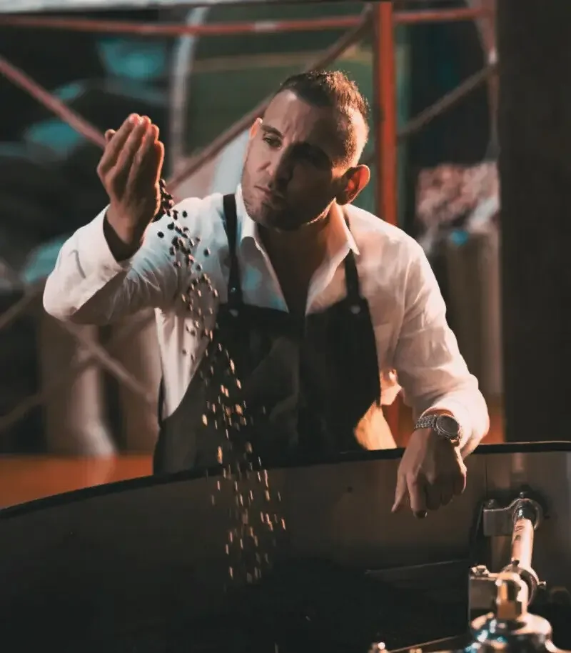 Roaster letting freshly roasted coffee beans run through his hand